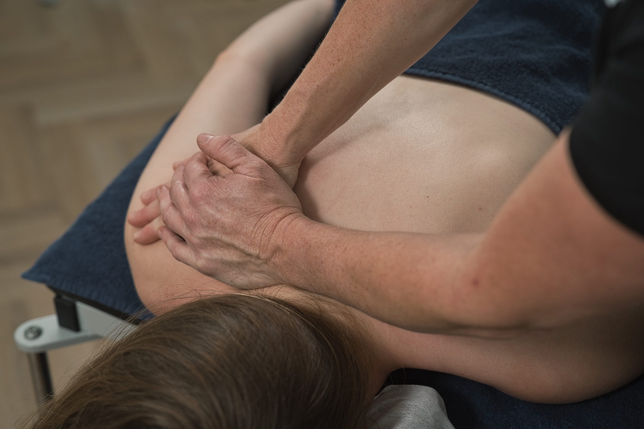 Behandlers hænder masserer patientens øvre ryg