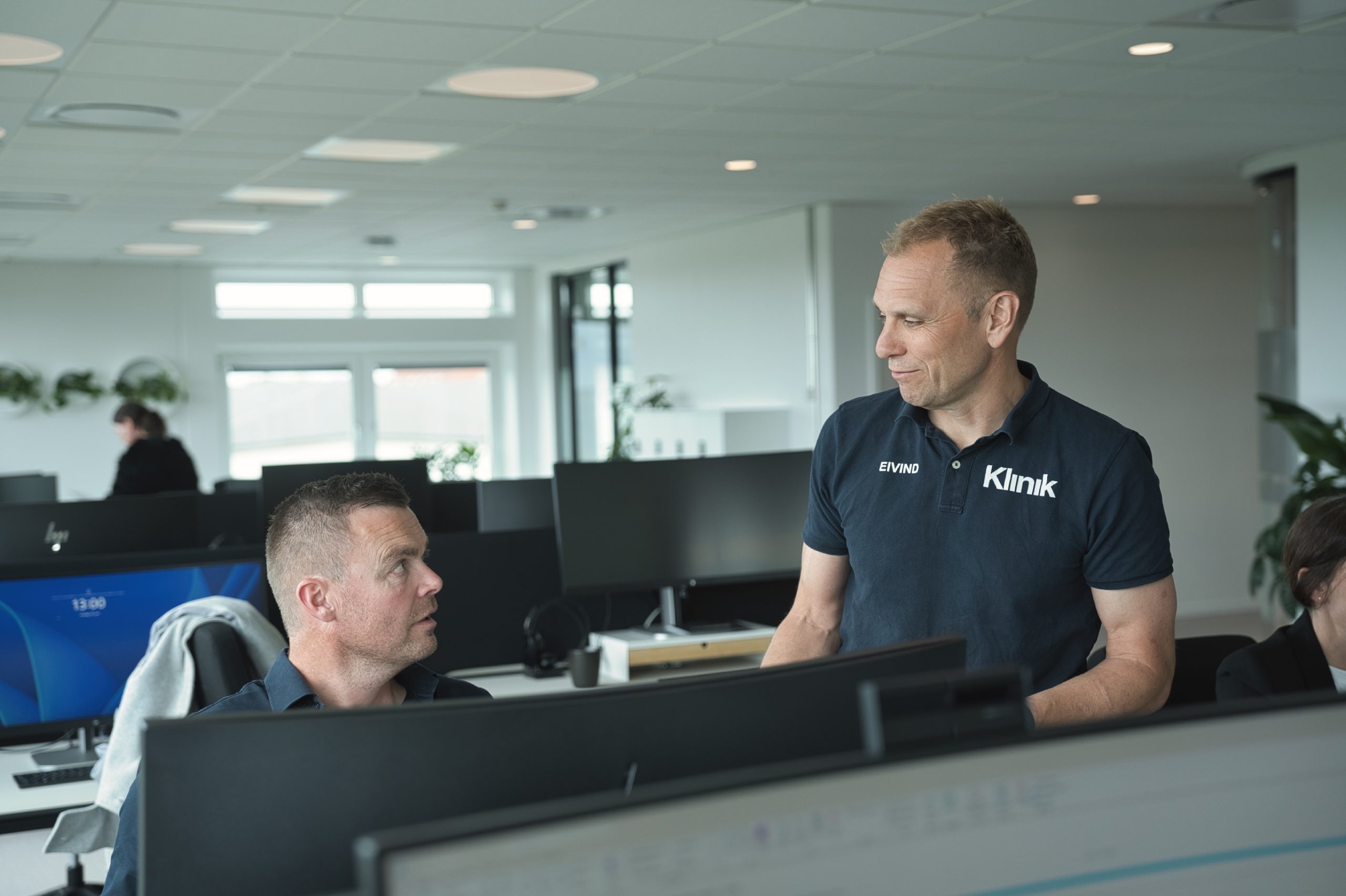 Tre kolleger arbejder ved hver sin skærm i et lyst kontorlandskab